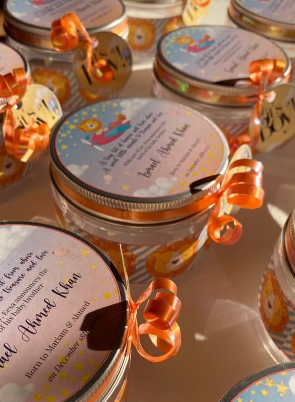 Baby shower announcement glass jars with custom tags and orange ribbons